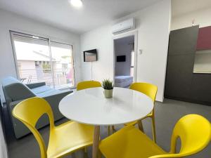 托尔托雷托Nuovo a 40 passi dal mare. A casa di “Bicca”的客房内的白色桌子和黄色椅子