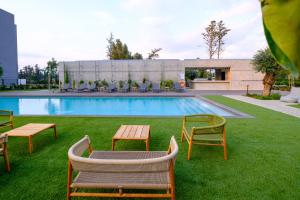 利马索尔Sunset Gardens的一个带椅子和桌子的草地游泳池