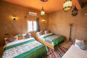 梅尔祖卡Kasbah Du Berger & Piscine的一间卧室配有两张床和一盏灯。