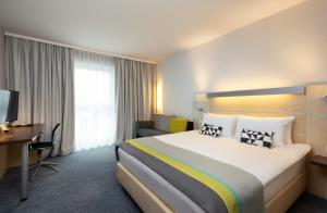 施瓦巴赫Holiday Inn Express Nürnberg-Schwabach的酒店客房设有一张大床和一张书桌。