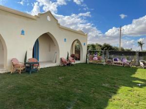 Qaryat at Ta‘mīr as SiyāḩīyahLake House by Tunisia Green Resort的一座白色的小建筑,配有椅子和庭院