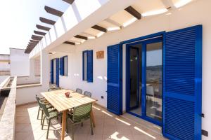 莱乌卡Appartamenti Marinelli - Santa Maria di Leuca的一间设有蓝色门和桌椅的用餐室