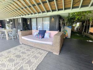 杰拉尔顿Luxe Family Retreat! Pool, Sauna, Playground, Netflix, Disney Plus的天井上的带枕头的柳条沙发