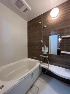 富良野Furano Yukisachi House的一间带大浴缸和镜子的浴室