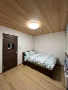 富良野Furano Yukisachi House的一间卧室设有一张床和木制天花板