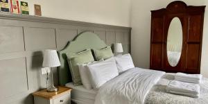 布兰德福德福鲁姆Portman Lodge的一间卧室配有一张带绿色床头板和白色枕头的床。