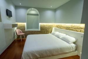 基多CASA ANABELA HOTEL BOUTIQUE的卧室配有白色的床和粉红色的椅子
