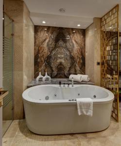 开罗Triumph Luxury Hotel的带浴缸的浴室和石墙
