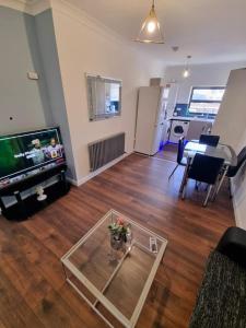 伦敦Beautiful Modern Apartment on Wick Lane的一间带电视和玻璃桌的客厅