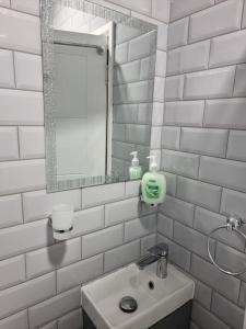 伦敦Beautiful Modern Apartment on Wick Lane的白色瓷砖浴室设有水槽和镜子