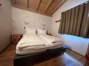 利维尼奥Hotel Le Alpi的一张带白色床单和枕头的床