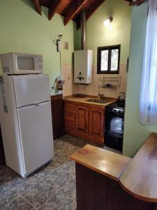 卡皮亚德尔德尔蒙特Cabañas El Aguaribay的厨房配有白色冰箱和水槽