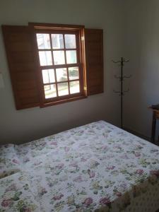 蒂拉登特斯Casa Almeida的一间卧室配有一张带花卉床罩的床和窗户。