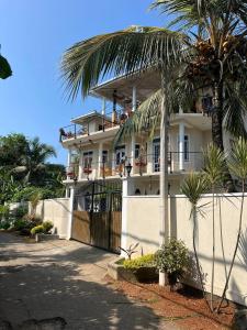 乌纳瓦图纳Habibi Hostel & Restaurant的白色的建筑,有栅栏和棕榈树