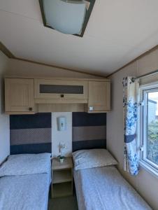 韦茅斯PEACEFUL HOMELY Caravan IN LOVELY CUL DE SAC Littlesea Haven Weymouth的小型客房 - 带2张床和窗户