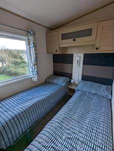 韦茅斯PEACEFUL HOMELY Caravan IN LOVELY CUL DE SAC Littlesea Haven Weymouth的小型客房 - 带2张床和窗户