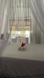帕洛米诺Casa Yuluka en la playa, Palomino的一张带两条毛巾和鲜花的白色床