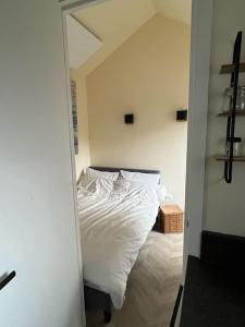 海牙Renovated & private Tinyhouse Den Haag short stay appartment的一间卧室配有一张带白色床单和镜子的床