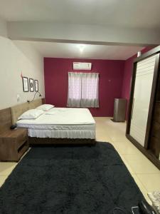卡莫辛Ilha do amor的一间卧室配有一张床和紫色的墙壁