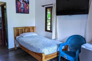 CañasDidi Lodge - Cabaña cálida y acogedora!的一间小卧室,配有一张床和一张蓝色椅子
