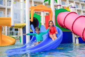 马拉戈日Maragogi Brisa Exclusive Hotel的两名儿童在水上公园滑梯上玩耍