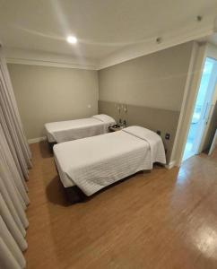圣保罗Transamerica Executive Bela Cintra (Paulista)的小型客房铺有木地板,配有两张床。