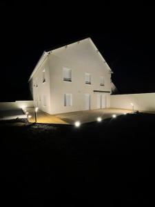 Maison au sein d’un corps de ferme.的白色的房子,晚上有灯在前面