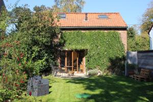 JodoigneGîte l'Ecurie的一座小房子,有绿色常春藤遮盖的院子