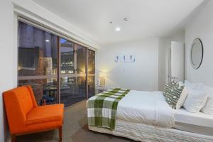 奥克兰CBD Stunner - Skytower View - WIFI - Netflix的一间卧室配有一张床和一张橙色椅子
