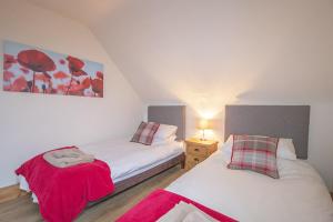 德里门Craigievern Cottage的卧室配有两张挂着红色鲜花的床。