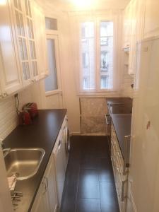 巴黎Cosy Appart Prince Auteuil的厨房配有白色橱柜、水槽和柜台。
