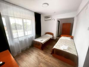 BechetHotel Tata Si Fii的小房间设有两张床和窗户
