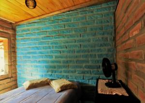 托雷斯Hostel CASA DA PEDRA CHATA的一间卧室设有蓝色砖墙和一张床