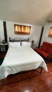 Santa MaríaKoi's House - Quebradillas de Dota的卧室配有白色的床和红色椅子