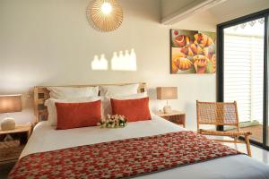 波尔兰特LES GALETS ROUGES LODGES & SPA的一间卧室配有一张带红色枕头的大床