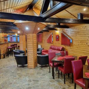 TeşilaVila Karina的餐厅设有木墙和红色的桌椅
