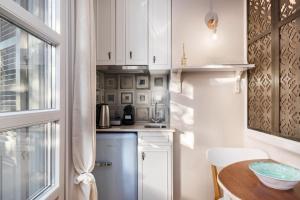 AnemómylosWell Apartments by Skyloft Corfu的小厨房配有白色橱柜和桌子