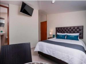库斯科Hotel Luna de Oro Cusco的一间卧室配有一张带蓝色枕头的床和电视。