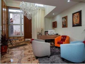 库斯科Hotel Luna de Oro Cusco的客厅配有椅子、桌子和吊灯。