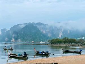 班奥南矛VILLA LOVED BEACH AO NAM MAO krabi的水面上的三艘船,背景是群山