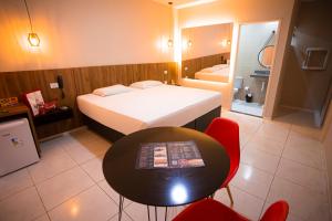 阿拉皮拉卡Lotus Motel Guaribas的卧室配有一张床和一张桌子及椅子