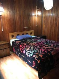 塞鲁阿苏尔La Casa Roja Cerro Azul的卧室内的一张床位,设有木墙和木地板