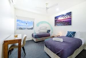 达尔文ZEN BY THE WATER - Darwin's Premier Ocean View Family Retreat的一间卧室配有两张床、一张桌子和一张桌子