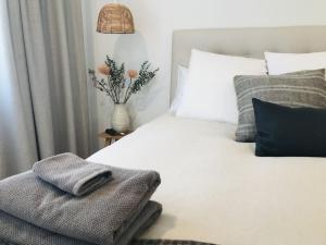 科夫斯港Seabirds Cottage的卧室配有白色的床和花瓶