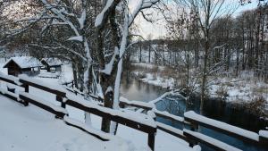 KaltanėnaiNamelis Šiaurėje的一条被雪覆盖的河岸围起来的围栏