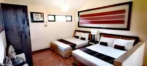长滩岛Unit 306 Alta Vista de Boracay by David的酒店客房设有两张床,墙上挂有绘画作品