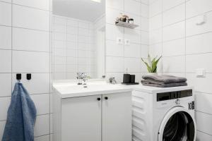 RåholtModerne leilighet - nært flyplass - lader for elbil的白色的浴室设有洗衣机和水槽。