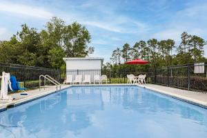 彭萨科拉Days Inn by Wyndham Pensacola I-10的一个带椅子和遮阳伞的游泳池