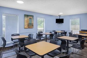 彭萨科拉Days Inn by Wyndham Pensacola I-10的一间设有桌椅的教室,房间拥有蓝色的墙壁