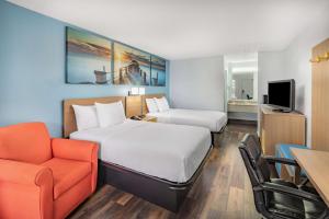 彭萨科拉Days Inn by Wyndham Pensacola I-10的酒店客房,配有两张床和椅子